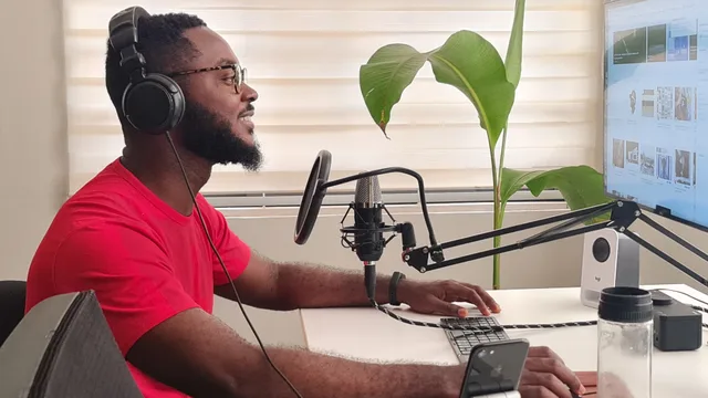 Man recording podcast in home studio with microphone, headphones, and computer screen. A monthly KPI routine for a podcast business for a small operation