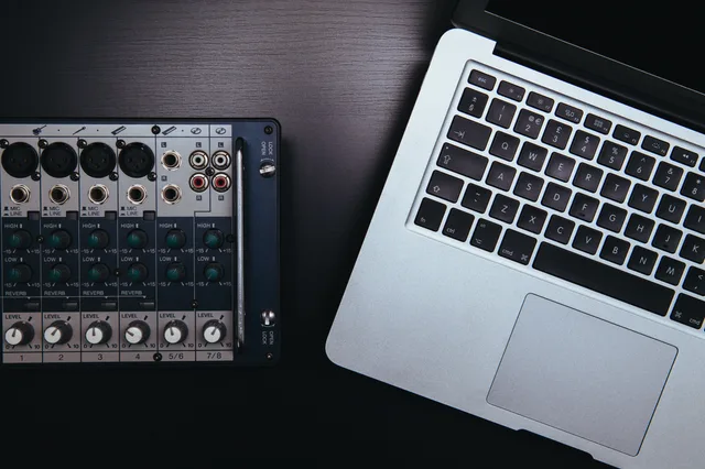 Close-up of audio mixer and laptop, essential for music production and sound editing. Podcast production tools: the features that matter and the ones that do not