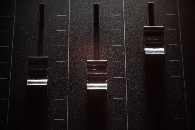 Details of faders of a mixing console, closeup view. Podcast sponsorship, one decision at a time