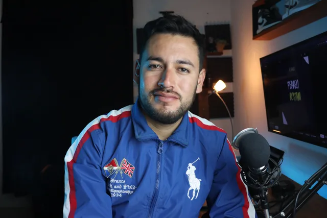 Man in a blue jacket with microphone recording a podcast in a home studio setup. What is changing in the podcast market in 2027?